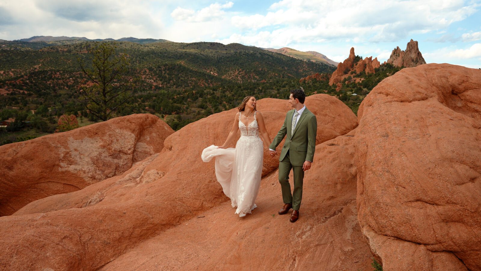Couple walking hand in hand across red rocks during Garden of the Gods wedding portraits in Colorado.