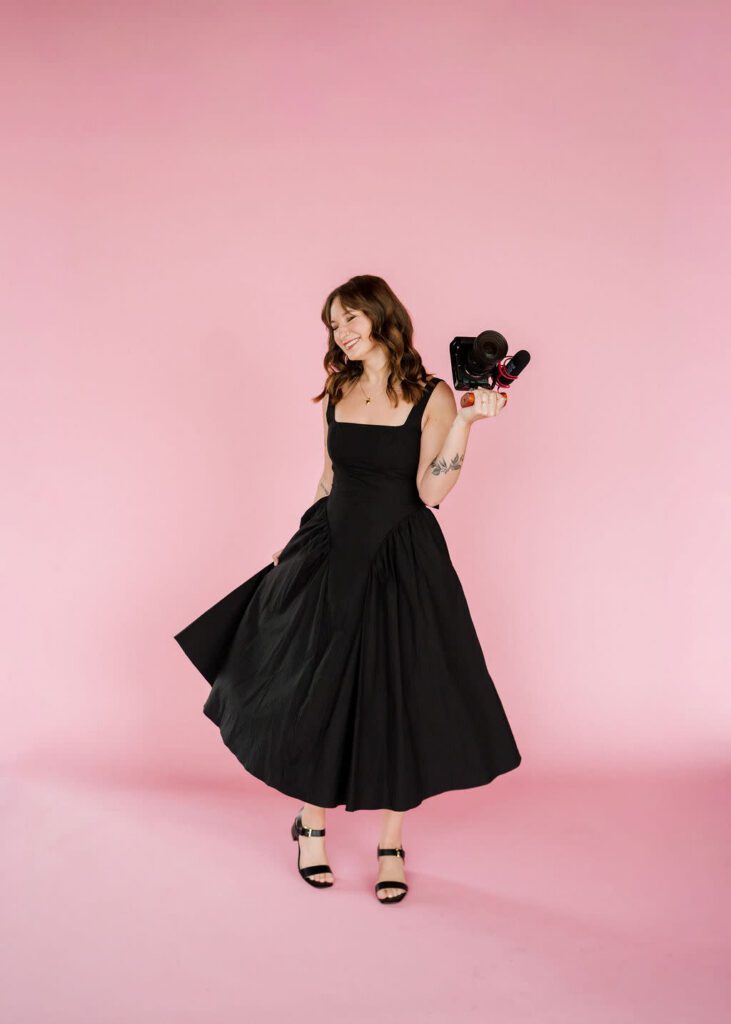 Holly, owner of Holly Kell Creative and Colorado wedding videographer posing with her gear for branding photos.