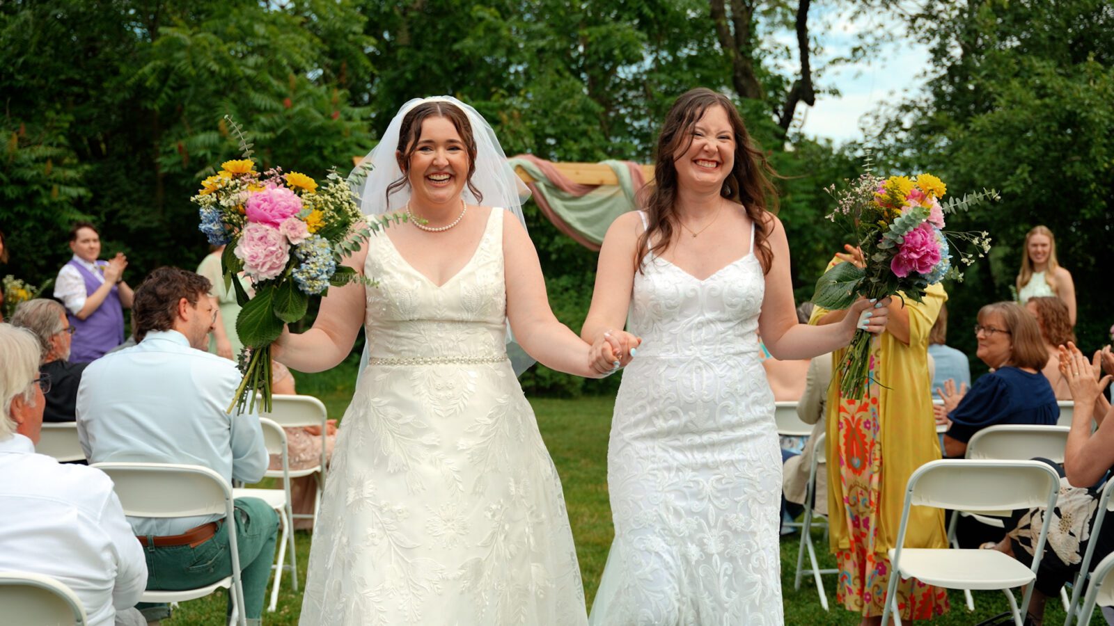 Newlyweds walking hand in hand down the aisle after their outdoor District 5 Schoolhouse wedding ceremony.